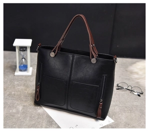 Black PU leather tote bag detail with front zipper pockets and brown top handles