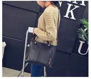 Fashionable black faux leather tote bag with brown straps styled on a casual female model