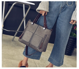 Detailed view of grey PU leather tote bag with brown straps worn by a model