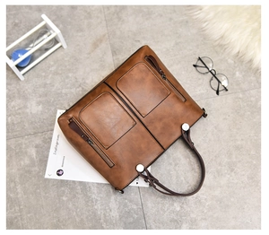 Flat lay of brown vintage leather tote bag with dual front pockets and shoulder strap