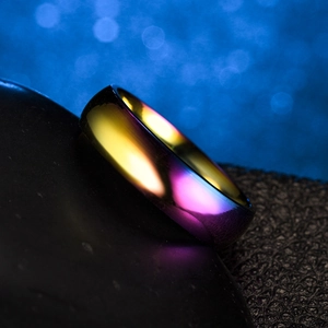Polished rainbow stainless steel ring on black stone background with blue bokeh