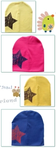 Detail of four colorful knit beanies with textured star prints for infants and children