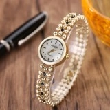 Detail of a vintage floral enamel watch with golden metal band on a display stand
