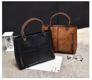 Detail view of vintage oil leather tote bags in black and caramel with front pockets