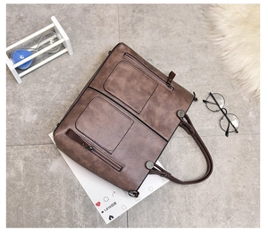 Detail view of dark brown retro tote bag with dual front pockets and metal zippers