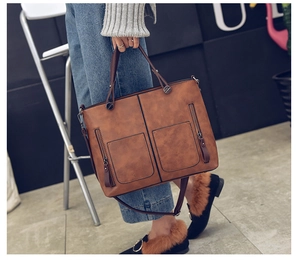 Detail of a large brown vintage faux leather tote bag with front pockets and zippers