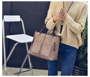 Detailed view of brown PU leather tote bag with dual zipper front pockets and handles