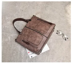 Macro view of vintage brown leather tote bag showing zippers and textured surface