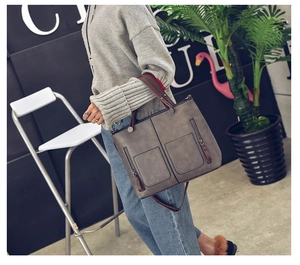 Chic grey leather tote bag with brown handles displayed in a stylish cafe setting