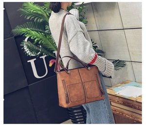 Brown vintage faux leather tote bag worn as shoulder bag by model in a minimalist room