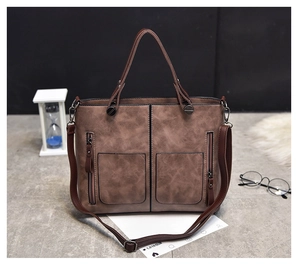 Macro detail of brown vintage PU leather tote showing dual front zippers and strap texture