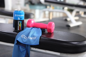 Blue cooling sports towel with pink dumbbells in a gym setting on a black bench