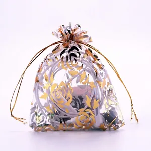 White organza drawstring gift bag with gold rose patterns and a semi-transparent finish