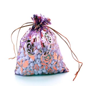 Detail of purple organza gift bag with gold rose pattern and drawstring closure
