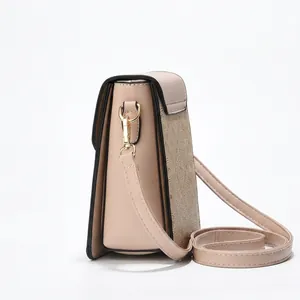 Detail view of beige matte PU leather mini square bag with golden hardware and black edging