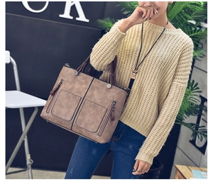 Detail showing vintage khaki faux leather tote bag with dual front zipper pockets on model