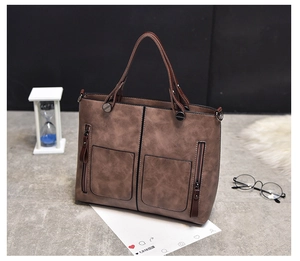 Detail view of brown vintage PU leather tote bag with dual zipper front pockets and handles