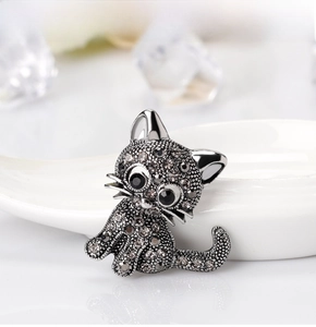 Macro shot of a cat brooch featuring grey rhinestones on a white ceramic tray