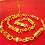 Detail of gold chunky hip hop chain necklace with round and bar links on red fabric