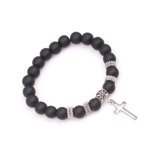 Detailed view of matte black volcanic stone beads and silver cross charm on yoga bracelet