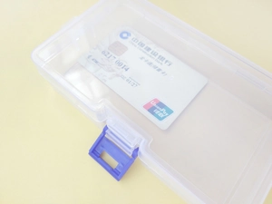 Close-up of clear plastic storage box with blue buckles and credit card for scale