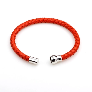 Orange braided leather bracelet with a round silver magnetic metal clasp on white background