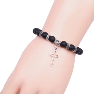Matte black volcanic stone yoga bracelet with silver cross pendant on a wrist