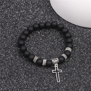 Detail of matte black beads and silver cross pendant on yoga bracelet with elastic cord