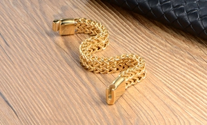 Detail of golden woven titanium steel bracelet with magnetic clasp on wooden surface