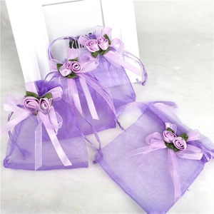 Detail of purple organza gift bag featuring decorative ribbon roses and drawstring closure