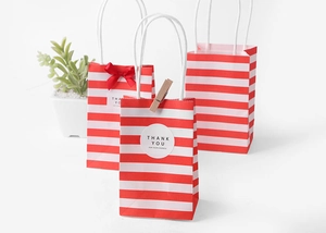 Detail of red striped kraft paper gift bags with handles and decorative thank you stickers