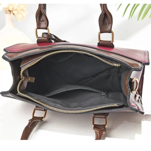 Detail view of burgundy tote bag with contrast stitching and multi-pocket interior layout