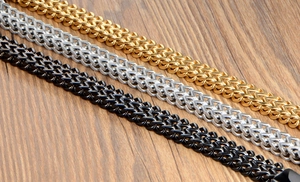 Detail of double-row stainless steel bracelets in gold, silver, and black finish on wood