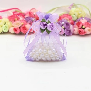 Detail of purple organza drawstring gift bag with faux rose and white pearls