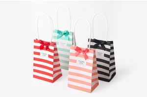 Detail showing four colorful striped paper gift bags with ribbon bows and thank you tags