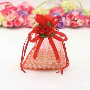 Detail of red organza gift bag with rose drawstring and pink pearls inside