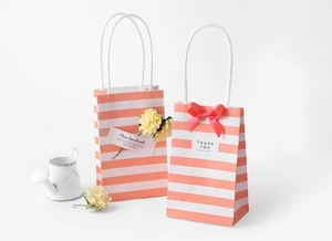 Detail of white and pink striped gift bags with floral decor and Thank You cards
