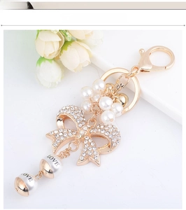 Detail of crystal bow keychain with pearls and LOVE letter beads on white background
