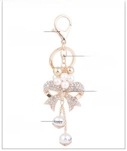 Detail of a sparkling bow-shaped keychain with white rhinestones and pearl pendant