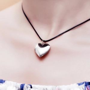 Polished silver heart locket pendant on black cord necklace worn by a model