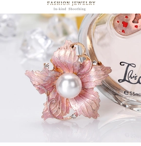 Macro shot of pink floral brooch with a large central pearl and sparkling rhinestones