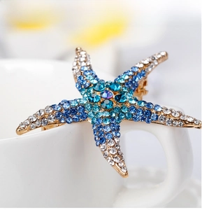 Macro shot of starfish brooch with blue and white rhinestones on a gold alloy base
