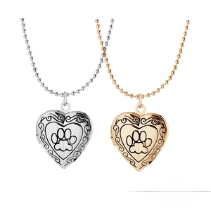 Detail of silver and gold heart locket pendants with paw prints and ornate engravings