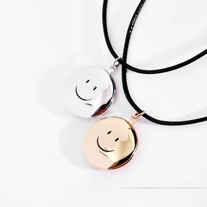Polished silver and rose gold smile charms on black cords against a white background