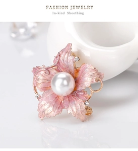 Macro detail of pink floral brooch with pearlescent petals and center pearl accent