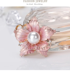 Close-up of pink enamel flower brooch with center pearl and sparkling zircon details
