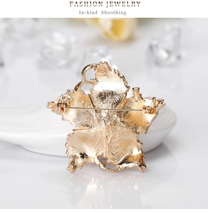 Detail view of the gold-tone flower brooch back featuring a secure rotating safety pin clasp