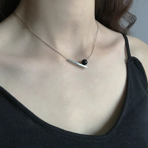 Close-up of a minimalist 925 silver necklace with black onyx pendant on a female model