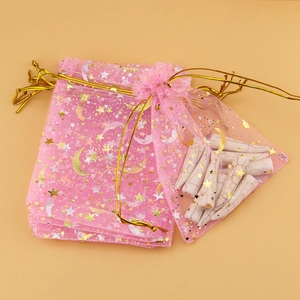 Detailed view of pink organza gift bags with gold moon stars and marble stone pendants