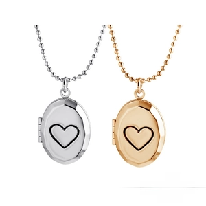 Macro detail of heart-engraved oval locket necklaces in polished silver and gold tones